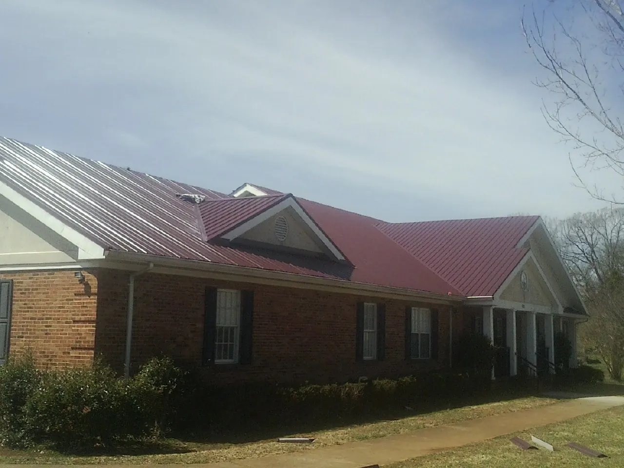 Red metal roof with gabled entries on a long brick building in Houston