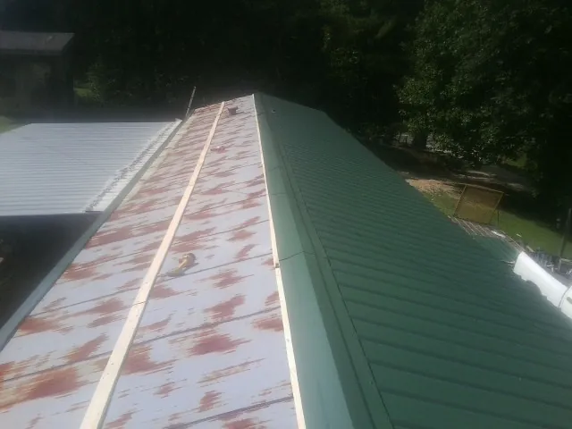 Old rusted panels beside newly installed green metal roofing — Wind Damage Roof Repair by Roofing Brothers in Houston